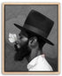 A black and white portrait of a man with a large hat, a long beard, and a butterfly resting on his nose.