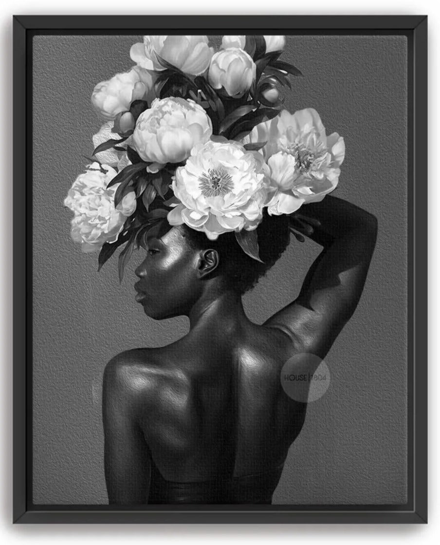 A black and white image of a woman with a large floral arrangement on her head, her back to the camera.