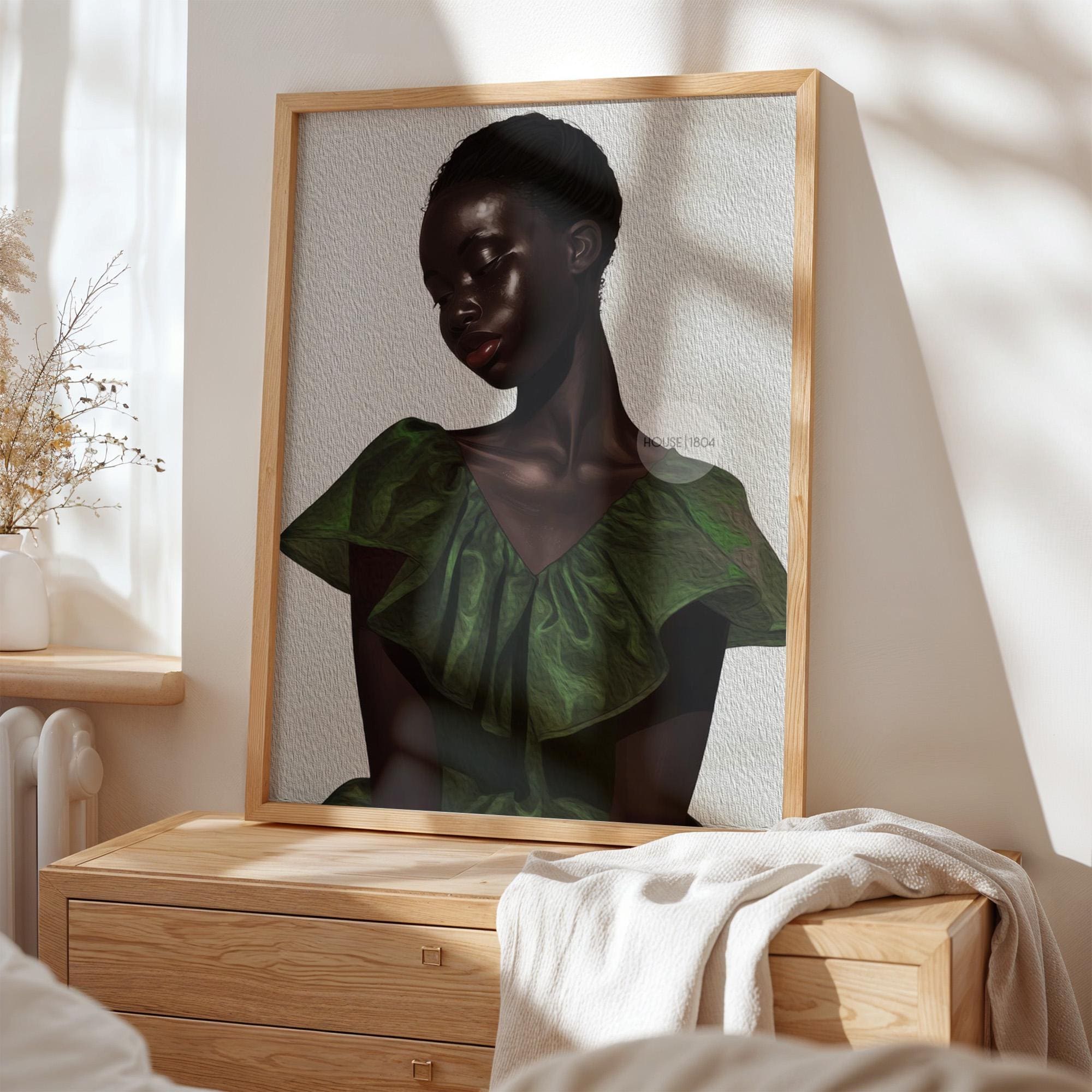 a framed portrait of a woman with a dark skin tone, wearing a green dress, displayed on a wooden dresser.