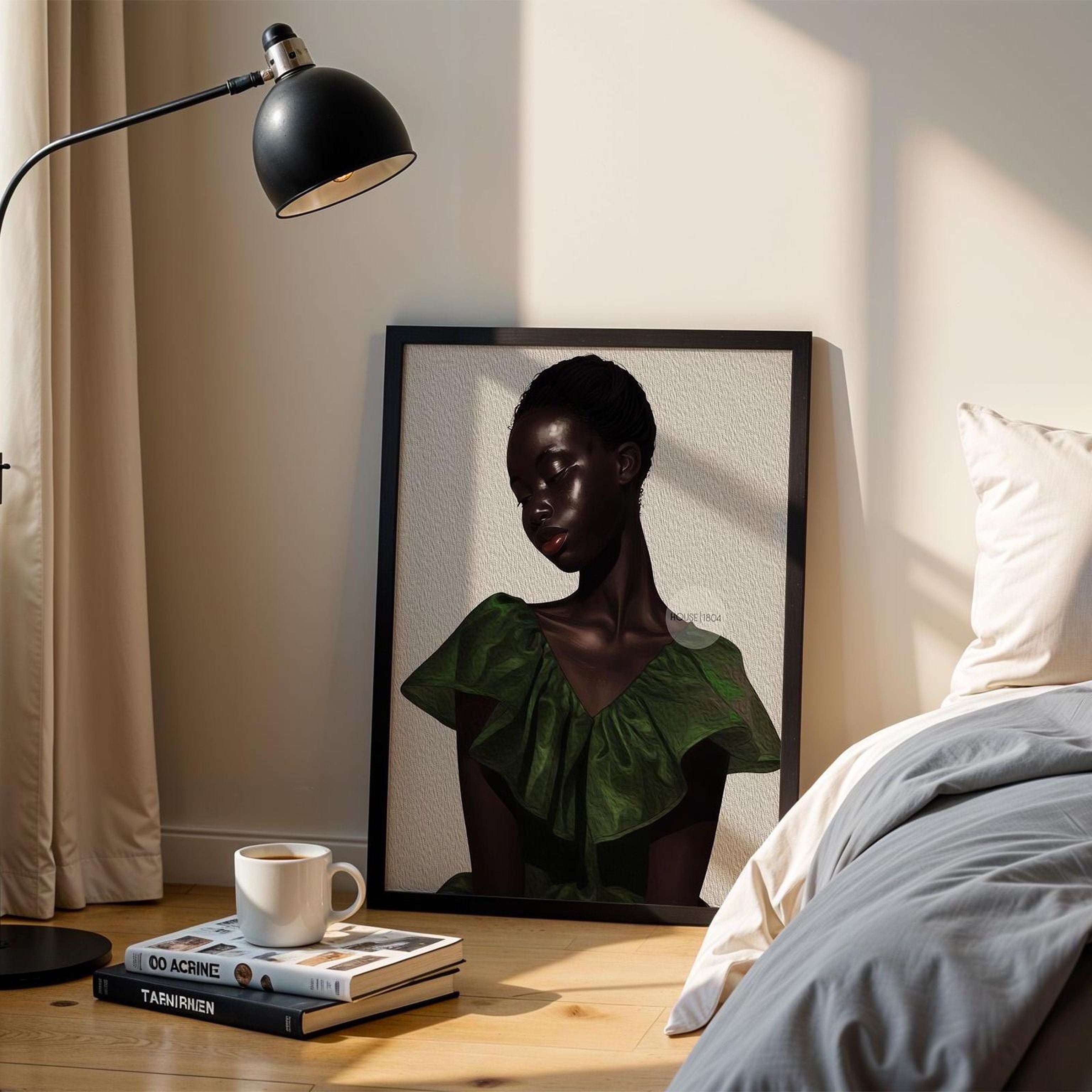a framed portrait of a woman in a green dress, placed on a wooden floor next to a bed with a gray comforter. There is a lamp and a stack of books on a nearby table.