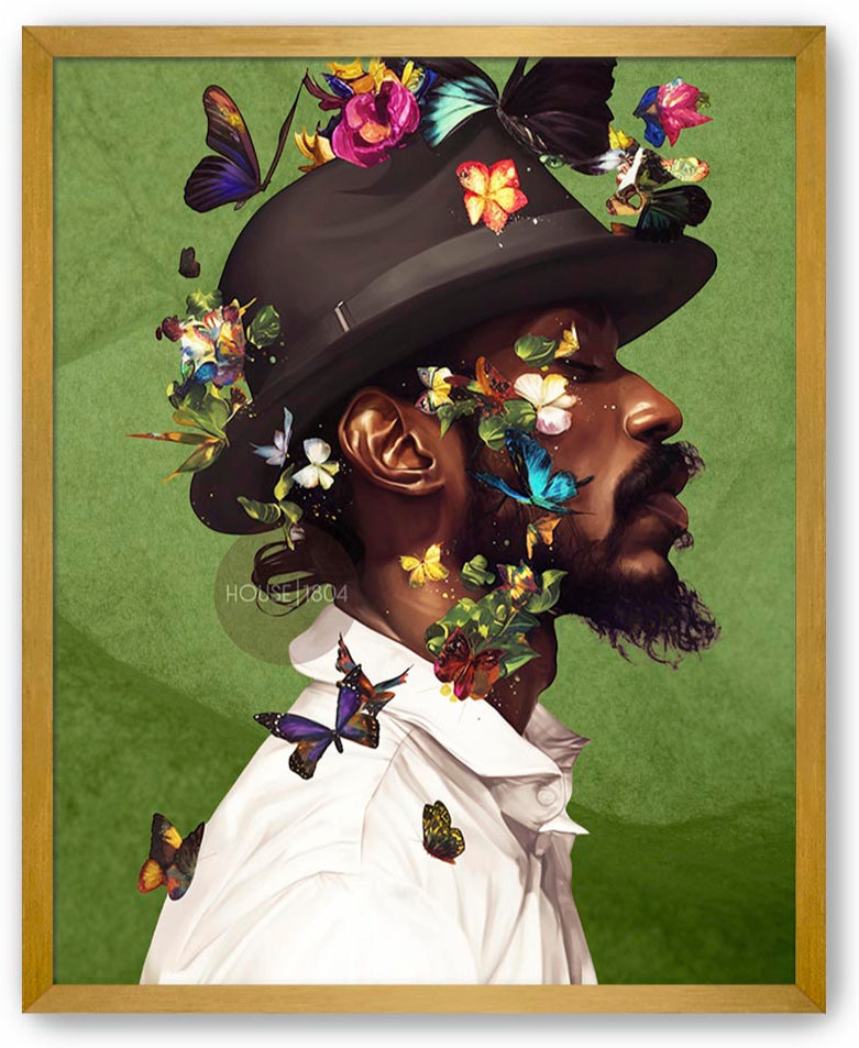 A man wearing a hat adorned with colorful butterflies and flowers, surrounded by a lush green background.